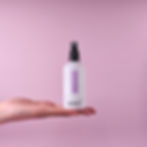 Omni White Musk Room Mist With Jasmine. Held By Hand In A Soft Lilac Background